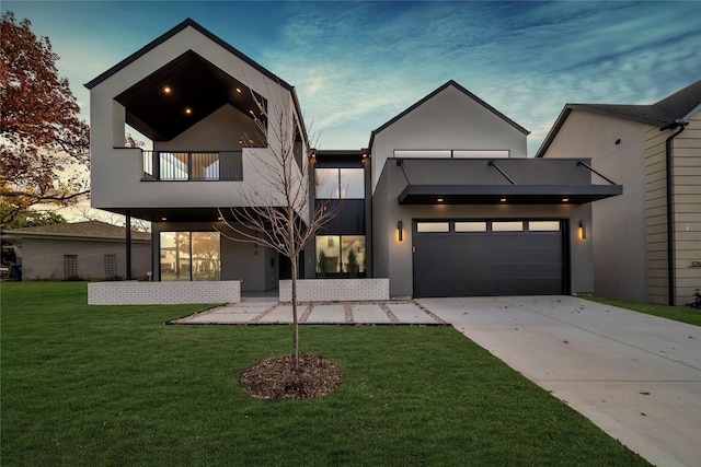 contemporary home with a front lawn, driveway, a garage, a balcony, and stucco siding