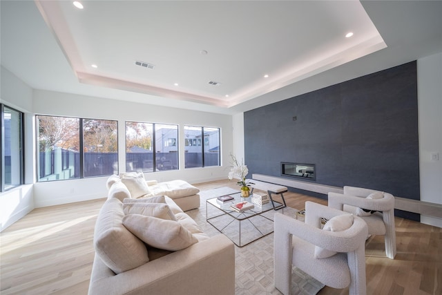 living room featuring a raised ceiling and light wood-type flooring