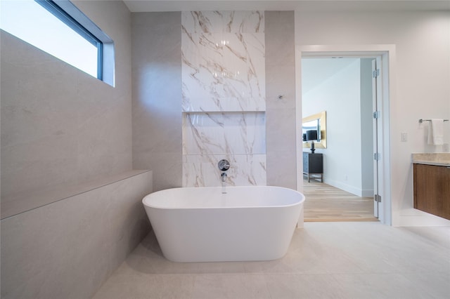 bathroom featuring a tub, hardwood / wood-style floors, vanity, and tile walls