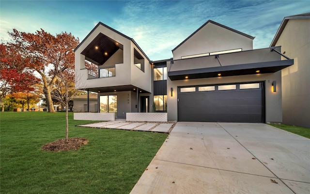 contemporary home featuring a front lawn, driveway, a balcony, and stucco siding