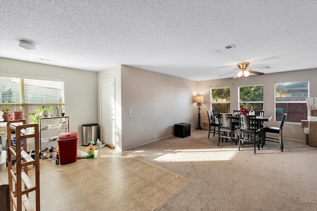 carpeted dining room with a textured ceiling and ceiling fan