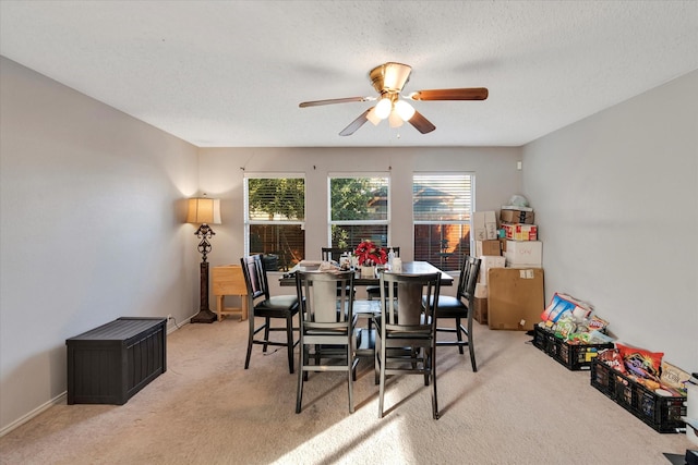 carpeted dining room with a textured ceiling and ceiling fan