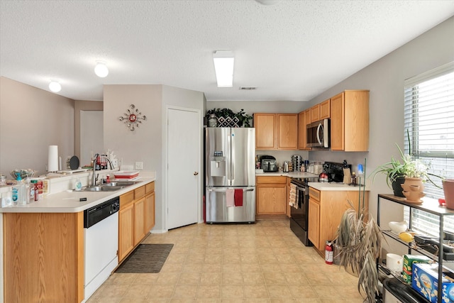 kitchen featuring stainless steel appliances, sink, a textured ceiling, and kitchen peninsula