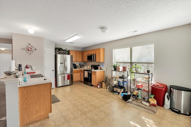 kitchen featuring a textured ceiling, sink, and appliances with stainless steel finishes