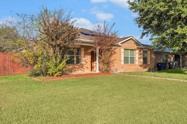 view of front of property with a front yard and solar panels