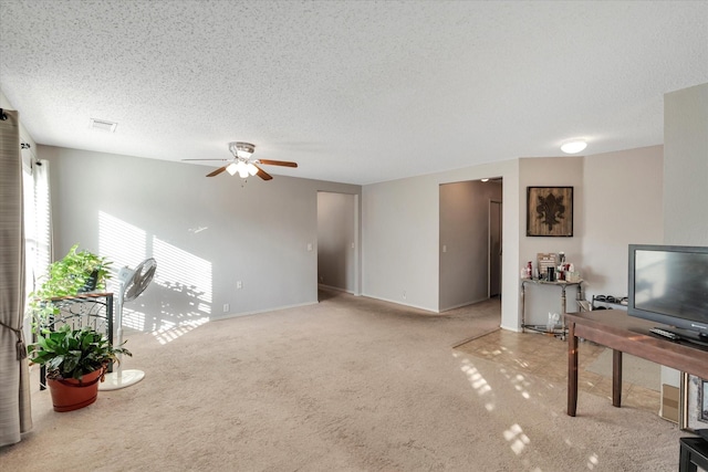 carpeted living room featuring ceiling fan and a textured ceiling