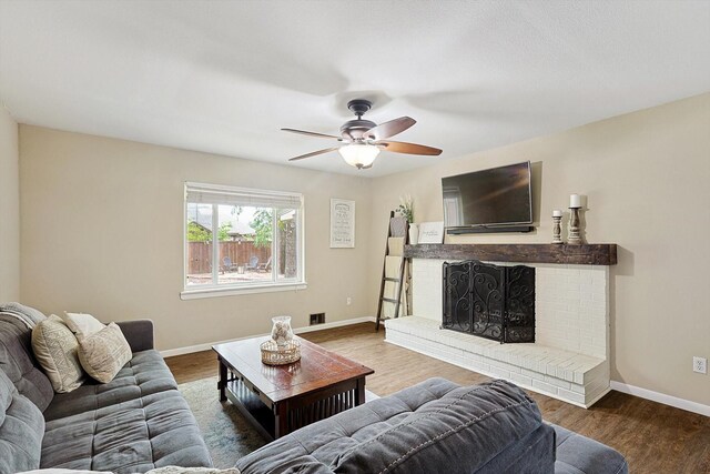 living room with hardwood / wood-style flooring, ceiling fan, and a brick fireplace