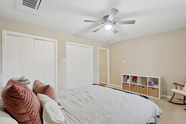 bedroom with multiple closets, ceiling fan, and light colored carpet