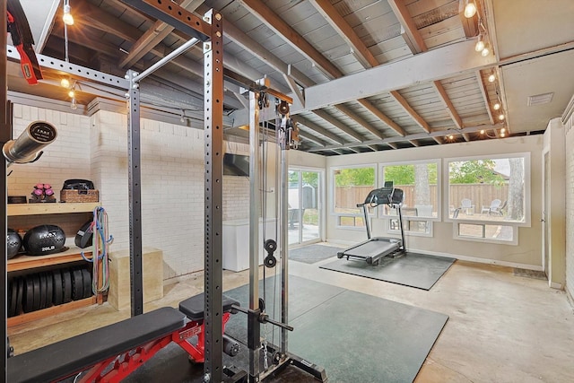 exercise area with brick wall and vaulted ceiling