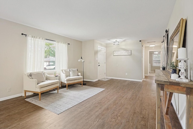 living area featuring a barn door and dark hardwood / wood-style flooring