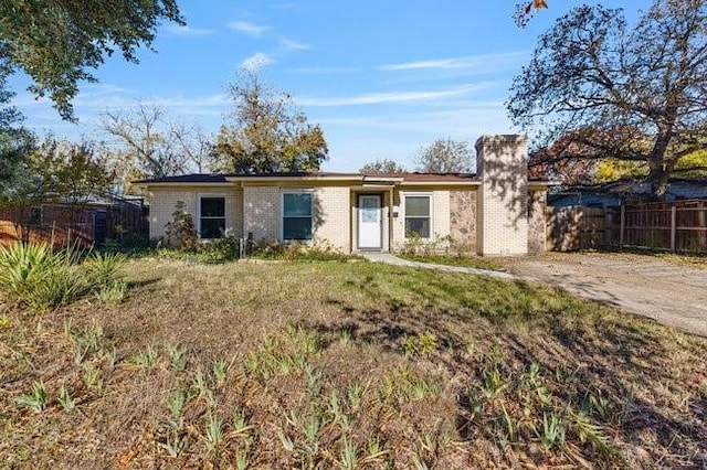 single story home with brick siding, a chimney, and fence