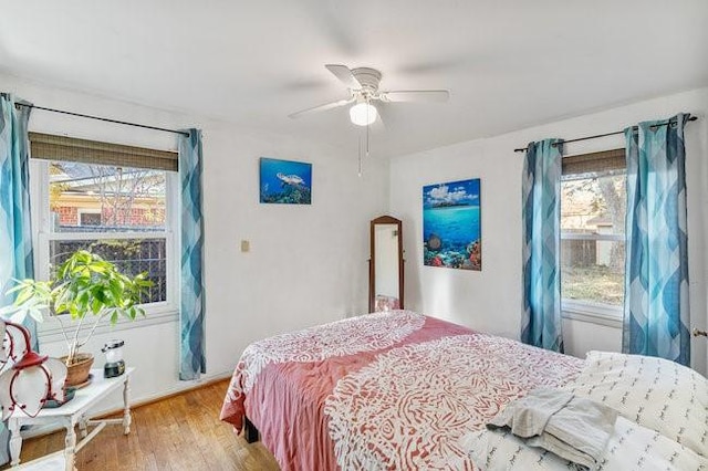 bedroom featuring multiple windows, ceiling fan, and wood finished floors