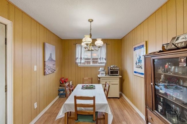 dining room featuring an inviting chandelier, light hardwood / wood-style flooring, and a textured ceiling