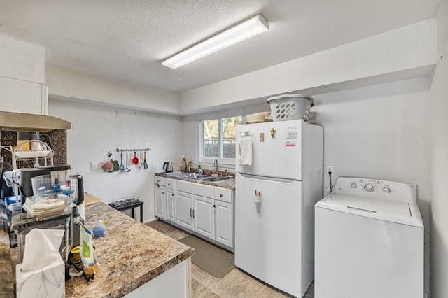 kitchen featuring washer / clothes dryer, sink, white cabinets, white refrigerator, and a textured ceiling