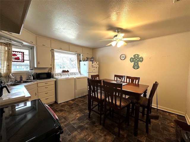 dining space featuring ceiling fan, sink, a textured ceiling, and independent washer and dryer