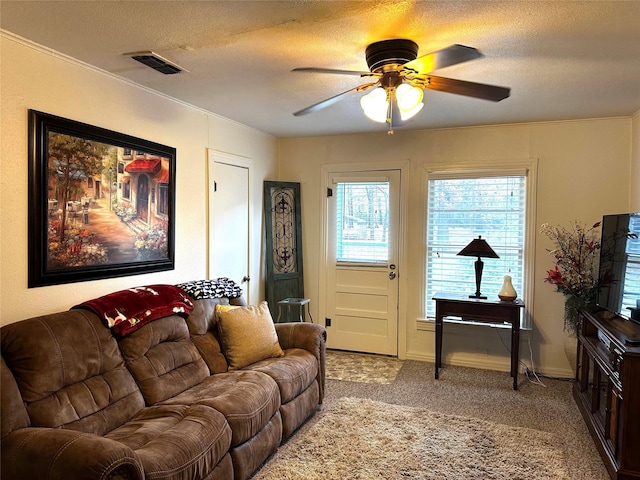 carpeted living room featuring ceiling fan, ornamental molding, and a textured ceiling