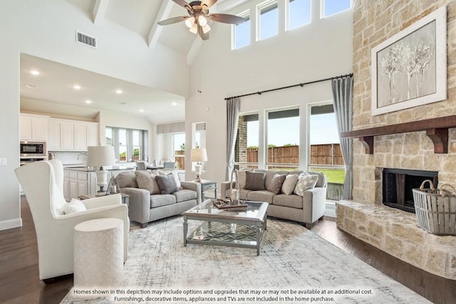 living room with hardwood / wood-style floors, a fireplace, beamed ceiling, and ceiling fan