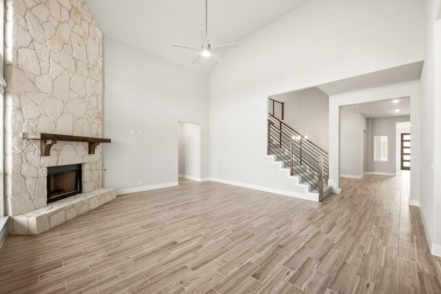 living room with beamed ceiling, a towering ceiling, hardwood / wood-style floors, and a fireplace