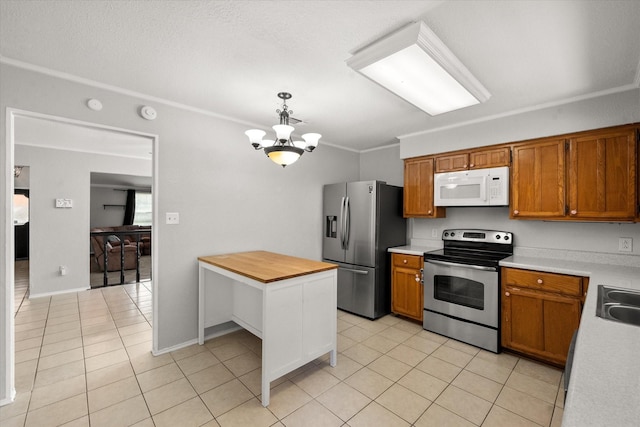 kitchen with pendant lighting, sink, light tile patterned flooring, and appliances with stainless steel finishes