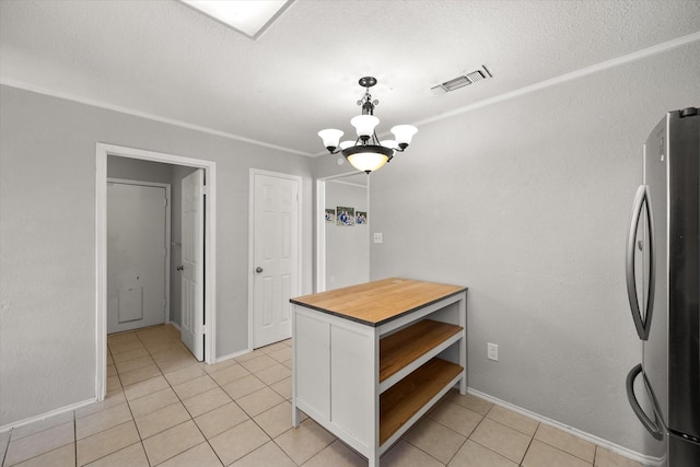 kitchen with pendant lighting, light tile patterned floors, stainless steel fridge, white cabinetry, and a chandelier