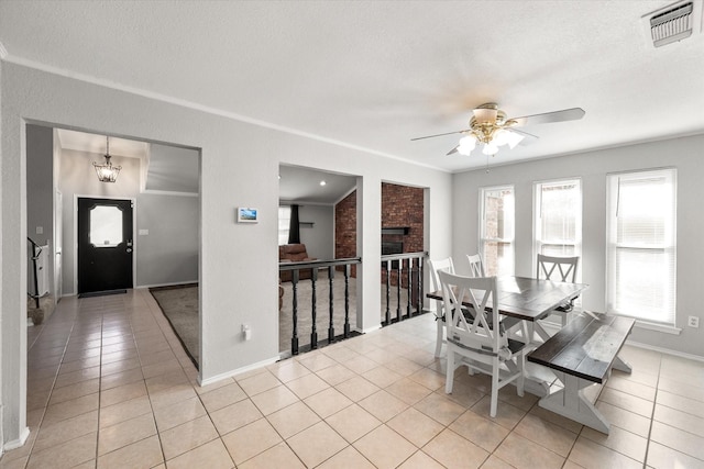 tiled dining space featuring a fireplace, ceiling fan with notable chandelier, and a textured ceiling