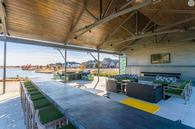 view of patio / terrace with a water view, an outdoor hangout area, and an outdoor bar