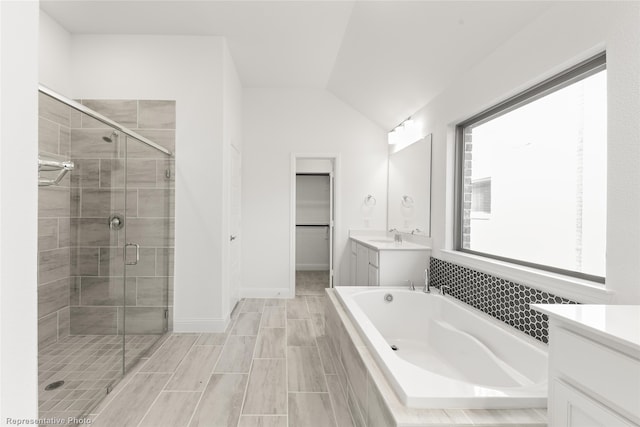 bathroom featuring vanity, shower with separate bathtub, and vaulted ceiling