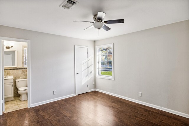 unfurnished bedroom with hardwood / wood-style floors, ensuite bathroom, and ceiling fan