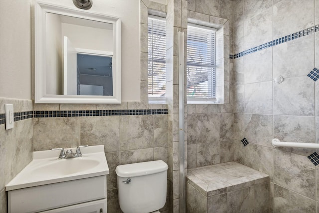 bathroom featuring vanity, toilet, tile walls, and a tile shower