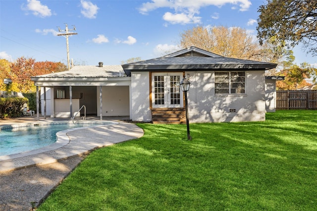 rear view of house with a fenced in pool, a patio area, and a lawn