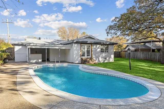 back of property with a fenced in pool, a patio area, a yard, and french doors