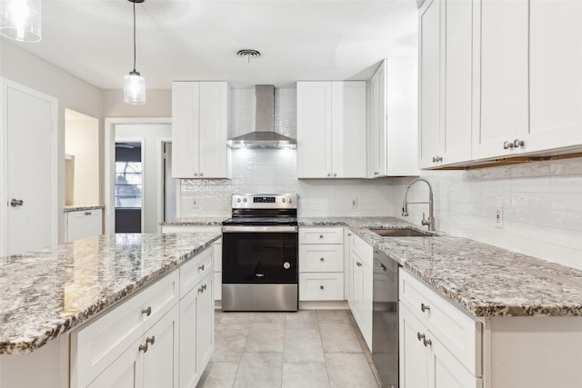 kitchen featuring sink, wall chimney range hood, pendant lighting, white cabinets, and appliances with stainless steel finishes