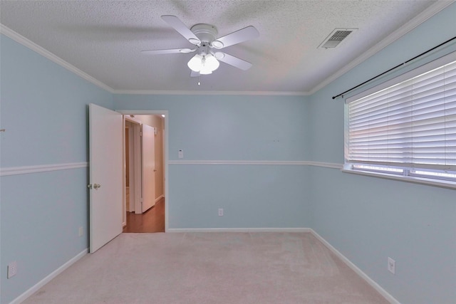 carpeted empty room featuring a textured ceiling, ceiling fan, and crown molding