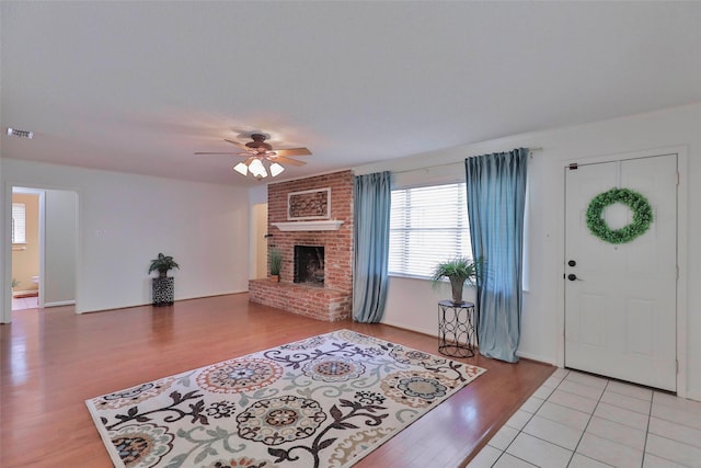 entryway with ceiling fan, light wood-type flooring, and a brick fireplace