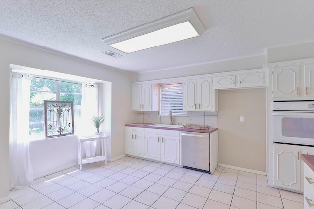 kitchen featuring dishwasher, light tile patterned flooring, white cabinetry, and sink