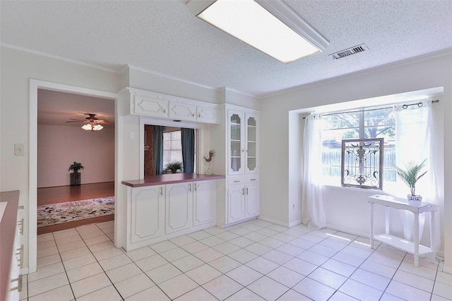 kitchen with a textured ceiling, ceiling fan, white cabinets, and light tile patterned floors