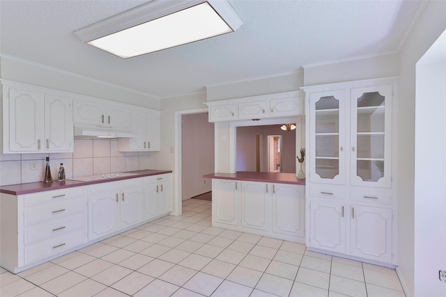 kitchen with decorative backsplash, white cabinetry, crown molding, and electric cooktop