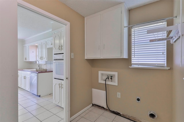 laundry room featuring sink, hookup for an electric dryer, hookup for a washing machine, a textured ceiling, and light tile patterned flooring