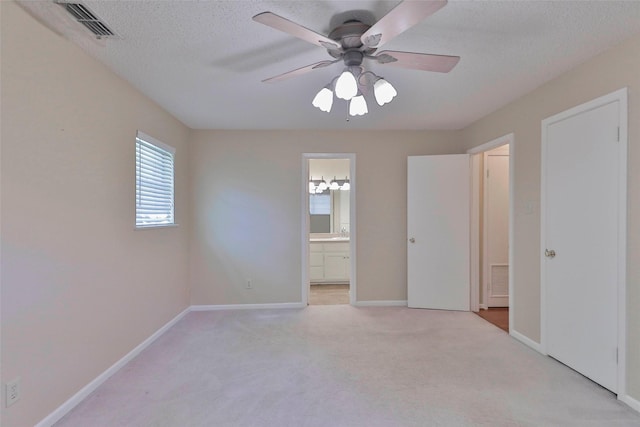 unfurnished bedroom with light carpet, a textured ceiling, ensuite bath, and ceiling fan