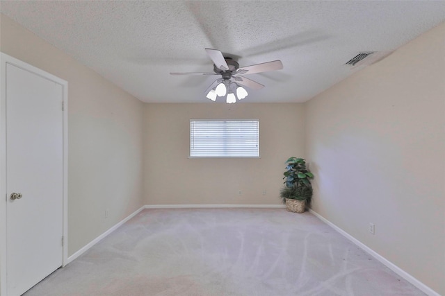 spare room with a textured ceiling, ceiling fan, and light carpet