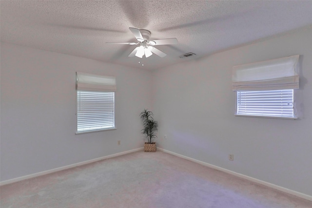 carpeted empty room featuring ceiling fan and a textured ceiling