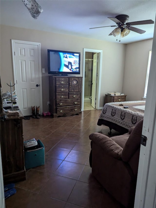 bedroom with ceiling fan, dark tile patterned floors, and ensuite bathroom