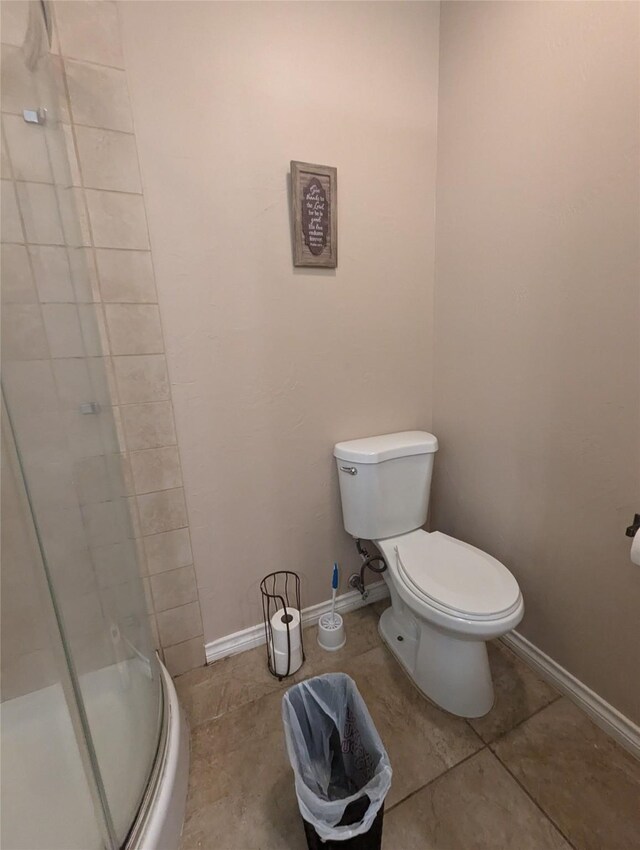 bathroom featuring tile patterned flooring, toilet, and walk in shower