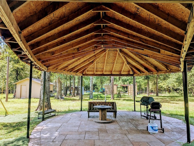 view of property's community featuring a lawn, a patio, and a shed