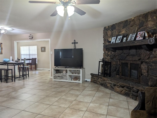 tiled living room with a stone fireplace and ceiling fan