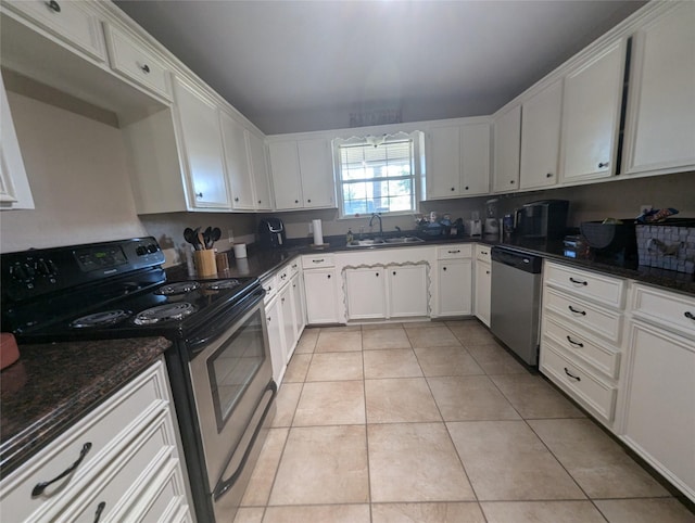 kitchen with white cabinets, sink, dark stone countertops, light tile patterned floors, and stainless steel appliances