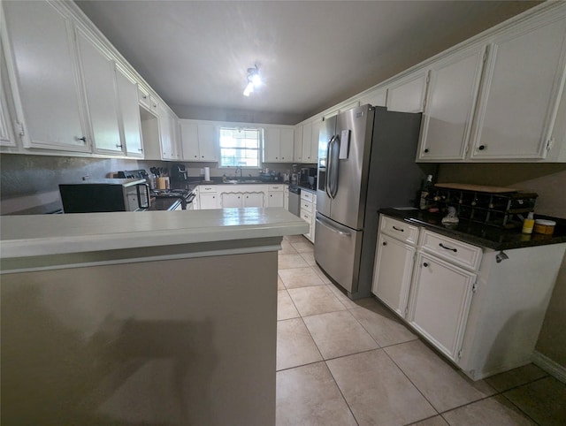 kitchen with sink, light tile patterned floors, kitchen peninsula, white cabinets, and appliances with stainless steel finishes