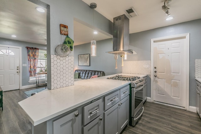 kitchen with kitchen peninsula, stainless steel range with gas cooktop, hanging light fixtures, and island exhaust hood