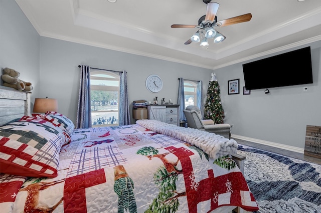 bedroom featuring ceiling fan, a raised ceiling, crown molding, and multiple windows