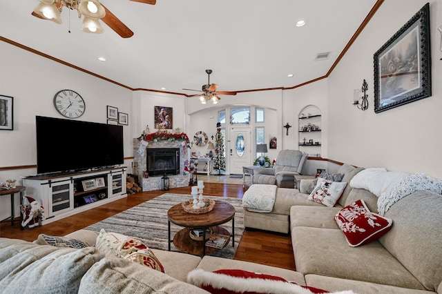 living room featuring a fireplace, dark hardwood / wood-style flooring, built in features, and crown molding